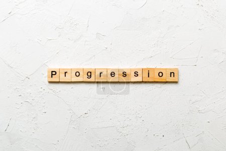 palabra de progresión escrita en bloque de madera. texto de progresión en la mesa de cemento para su diseño, concepto.