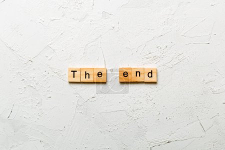 Das letzte Wort auf Holzblock geschrieben. Der Endtext auf dem Zementtisch für Ihre Gestaltung, Ihr Konzept.