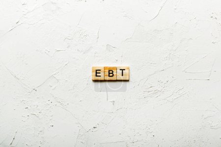 EBT word written on wood block. Abbreviation Earnings Before Taxes text on cement table for your desing, concept.
