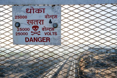 Téléchargez les photos : Danger Signe de 25.000 Volts sur un rail sur un pont près de Pune Inde. Ces panneaux sont régulièrement placés à des ponts sur des tronçons ferroviaires électrifiés en Inde. - en image libre de droit