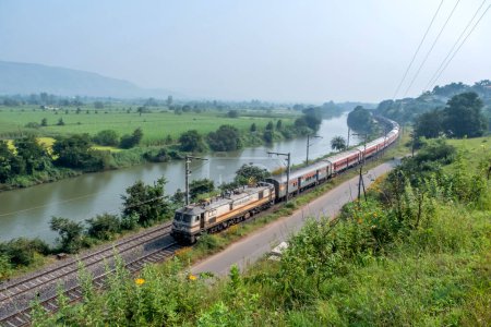Photo for Pune, India - October 15 2023: Passenger train hauled by a WAP7 electric locomotive near Pune India. - Royalty Free Image