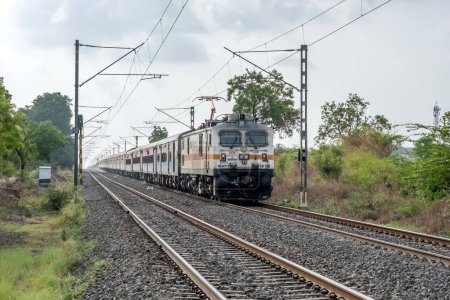Photo for Pune, India - June 18 2023: Passenger train hauled by a WAP7 electric locomotive near Pune India. - Royalty Free Image