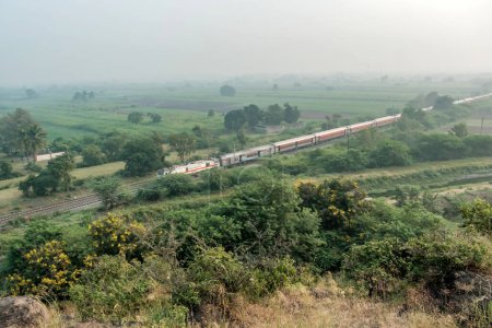 Photo for Pune, India - October 22 2023: Passenger train hauled by a WAP7 electric locomotive near Pune India. - Royalty Free Image