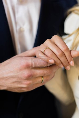 Photo for Elegant girl holds hand on her partners hand, pointing to their wedding rings in a closeup shot. Moment of emotional connection and unity. Focus is on details of hands, wedding rings, love - Royalty Free Image
