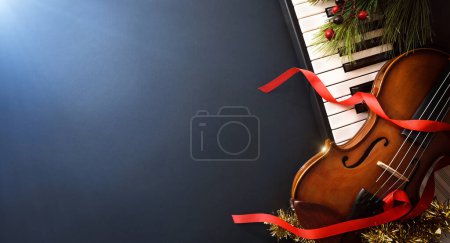 Foto de Fondo de concepto de evento musical navideño con piano y violín sobre mesa negra y luz azul. Vista superior. - Imagen libre de derechos