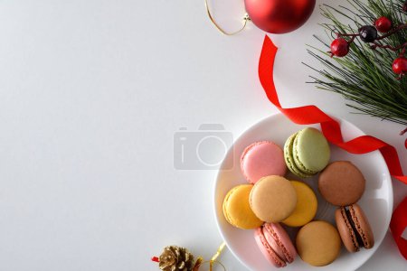 Téléchargez les photos : Assiette de macarons français de différentes saveurs sur une assiette sur une table blanche avec des décorations de Noël. Vue du dessus. - en image libre de droit