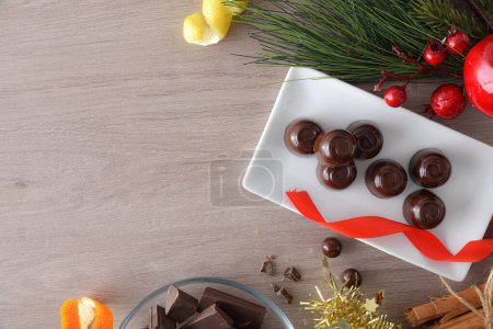 Téléchargez les photos : Bonbons au chocolat sur une plaque rectangulaire sur une table en bois avec des décorations de Noël. Vue du dessus. - en image libre de droit