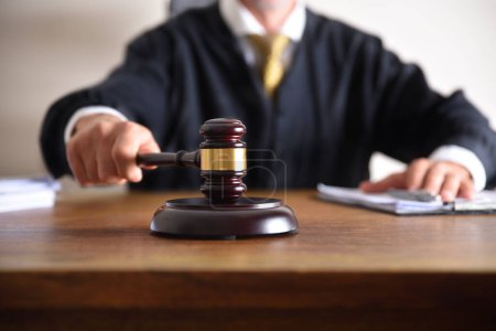 Foto de Detail of a judge passing sentence by hitting with the gavel on a wooden table closeup. Front view - Imagen libre de derechos