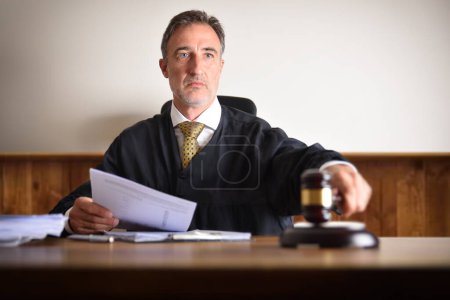 Téléchargez les photos : Détail d'un juge prononçant une sentence en frappant avec le marteau sur une table en bois. Vue de face - en image libre de droit