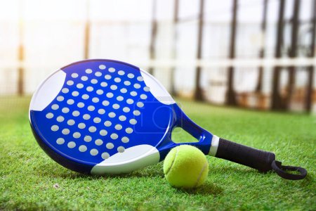 Foto de Padel racket and ball on artificial grass floor in outdoor court. Front view. - Imagen libre de derechos