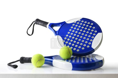 Foto de Set of paddle tennis rackets and balls the reflected on white table and white isolated background. Front view. - Imagen libre de derechos