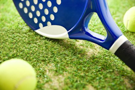 Foto de Padel rackets and balls on artificial grass floor in outdoor court. Front elevated view. - Imagen libre de derechos