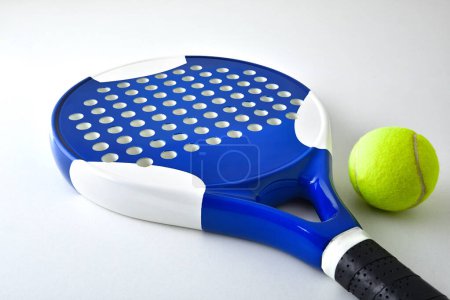 Foto de Padel racket on ball reflected on white table and white isolated background. Elevated view. - Imagen libre de derechos