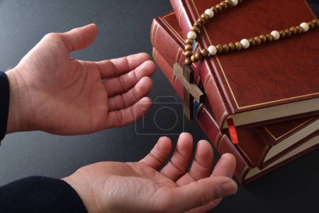 Foto de Cristiano rezando con las manos en alto con la mesa negra en el fondo con la Biblia. Vista elevada. - Imagen libre de derechos