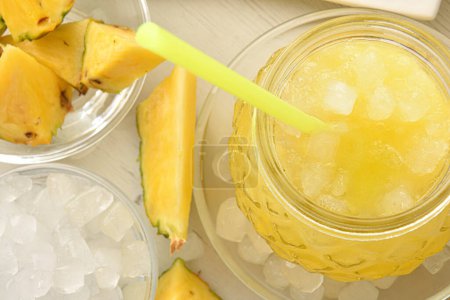 Detail des Glases mit kaltem Ananasgetränk mit Eis und rundherum geschnittenen Früchten. Ansicht von oben. Horizontale Zusammensetzung.