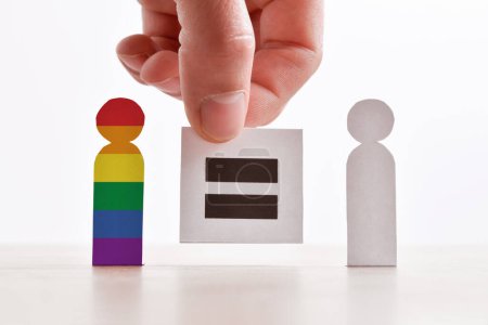 Foto de Comparación entre la diversidad sexual y de género con recortes de personas de papel y el letrero de mano con el mismo símbolo. - Imagen libre de derechos
