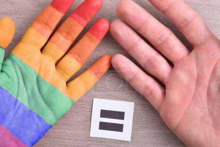 Foto de Igualdad entre la diversidad sexual y de género y heterosexuales con las manos sobre la mesa con signo con signo igual. - Imagen libre de derechos