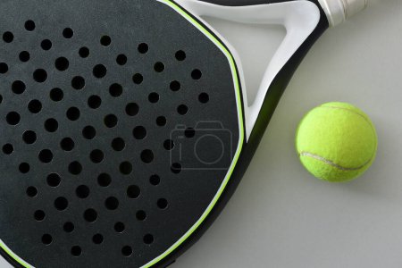 Foto de Detalle de raqueta y pelota de pádel blanco y negro sobre una mesa blanca. Vista superior. - Imagen libre de derechos