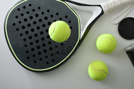 Foto de Raqueta de tenis de pádel blanco y negro y olla de bolas en una mesa blanca. Vista superior. - Imagen libre de derechos