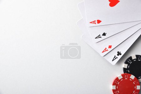 Téléchargez les photos : Arrière-plan avec des cartes d'as et de jetons pour parier isolé sur une table blanche. Vue du dessus. - en image libre de droit
