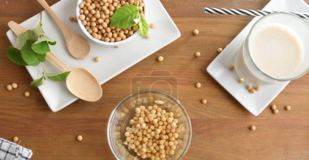 Foto de Remojo de soja y un tazón lleno de semillas para hacer bebida de soja en la mesa de madera rústica. Vista superior. - Imagen libre de derechos