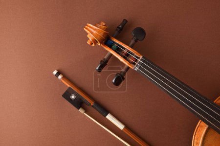 Photo for Detail of peg box and fingerboard of traditional stringed violin and bow on isolated gradient brown background.. Top view. - Royalty Free Image