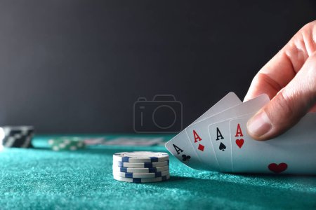 Foto de Mano que muestra cuatro ases jugando a las cartas en una mesa con alfombra verde con fondo oscuro y aislado. Vista frontal. - Imagen libre de derechos