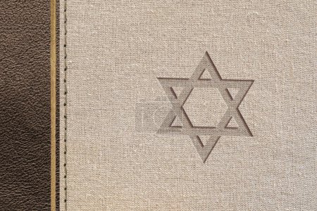 Diseño religioso judío marrón con textura de cuero y tela con la estrella de David grabada. Vista superior.