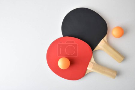 Deux raquettes de ping-pong et deux balles orange isolées sur une table blanche. Vue du dessus.