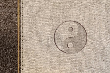 Diseño de filosofía taoísta marrón con textura de cuero y tela con yin-yang grabado. Vista superior.