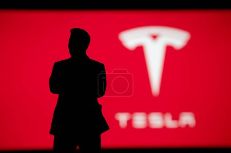 Téléchargez les photos : New York, États-Unis, 2. OCTOBRE 2022 : Silhouette d'homme d'affaires Elon Musk sur présentation Tesla, Logo de la société sur fond rouge - en image libre de droit