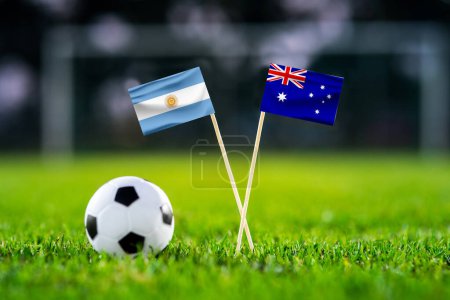 Photo for Argentina - Australia. Eight final, Round of 16 football match. Handmade national flags and soccer ball on green grass. Football stadium in background. Black space. - Royalty Free Image