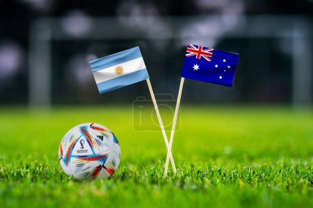 Téléchargez les photos : QATAR, DOHA, le 29 novembre. 2022 : Argentine - Australie. Tour de 16 matchs de football. Ballon officiel de la Coupe du Monde de Fifa Qatar 2022 sur herbe verte. Stade de football en arrière-plan, et drapeaux nationaux faits à la main - en image libre de droit