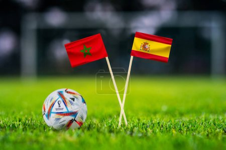 Photo for QATAR, DOHA, DECEMBER 2. 2022: Morocco - Spain Round of 16 football match. Official ball of Fifa world cup Qatar 2022 on green grass. Soccer stadium in background. Handmade national flags. - Royalty Free Image