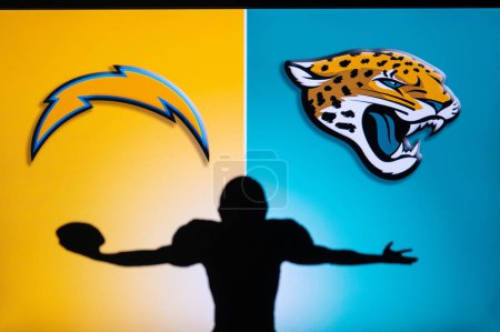 Téléchargez les photos : JACKSONVILLE, USA, JANUARY 10, 2023: Los Angeles Chargers vs. Jacksonville Jaguars. NFL Wild Card Round 2023, Silhouette of NFL player of american football. holding ball in hand. Big screen - en image libre de droit