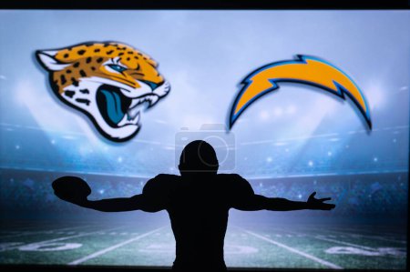Foto de JACKSONVILLE, USA, JANUARY 10, 2023: Los Angeles Chargers vs. Jacksonville Jaguars. NFL Wild Card Round 2023, Silhouette of NFL player of american football. holding ball in hand. Big screen - Imagen libre de derechos
