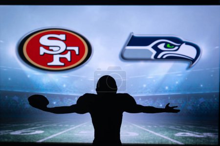 Photo for SAN FRANCISCO, USA, JANUARY 10, 2023: Seattle Seahawks vs. San Francisco 49ers. NFL Wild Card Round 2023, Silhouette of NFL player of american football. holding ball in hand. Big screen in background - Royalty Free Image