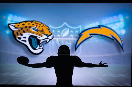 Photo for JACKSONVILLE, USA, JANUARY 10, 2023: Los Angeles Chargers vs. Jacksonville Jaguars. NFL Wild Card Round 2023, Silhouette of NFL player of american football. holding ball in hand. Big screen - Royalty Free Image
