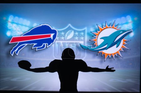 Téléchargez les photos : BUFFALO, USA, JANUARY 10, 2023: Miami Dolphins vs. Buffalo Bills. NFL Wild Card Round 2023, Silhouette of NFL player of american football. holding ball in hand. Big screen in background - en image libre de droit