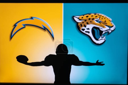 Téléchargez les photos : JACKSONVILLE, USA, JANUARY 10, 2023: Los Angeles Chargers vs. Jacksonville Jaguars. NFL Wild Card Round 2023, Silhouette of NFL player of american football. holding ball in hand. Big screen - en image libre de droit