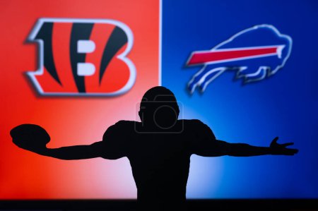 Téléchargez les photos : BUFFALO, USA, JANUARY 18, 2023: Cincinnati Bengals vs. Buffalo Bills. NFL Divisional Round 2023, Silhouette of NFL player of american football. holding ball in hand. Big screen in background - en image libre de droit