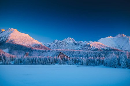 Téléchargez les photos : The serene beauty of a winter morning at Strbske pleso lake in Slovakia, with the High Tatras mountains in the background - en image libre de droit