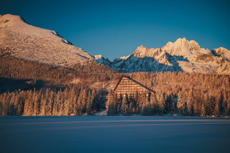Foto de Frozen winter morning at Strbske pleso lake under the High Tatras, with the last rays of the setting sun illuminating the snowy landscape. - Imagen libre de derechos