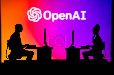 Foto de INDIA, NEW DELHI. JANUARY 30, 2023: Open AI. Innovating the Future: Silhouette of Two Software Developers and the Company's Logo in the Background - Imagen libre de derechos