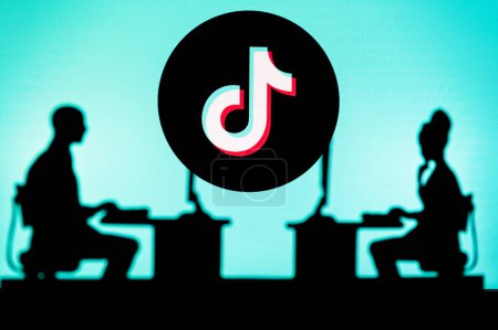 Foto de UK, LONDON. JANUARY 30, 2023: TikTok. Innovating the Future: Silhouette of Two Software Developers and the Company's Logo in the Background - Imagen libre de derechos
