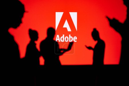 Foto de JAPAN, TOKYO. JANUARY 30, 2023: Adobe. Collaborating for Innovation: Silhouetted Web Developers in Action with Company Logo in Background - Imagen libre de derechos