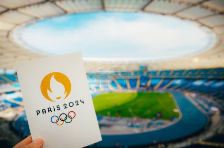 Photo for PARIS, FRANCE, JULY 7, 2023: Embracing the Symbol: Athlete Holds Iconic Emblem of Paris 2024 Summer Olympics, with Modern Stadium as a Majestic Backdrop. A Symbolic Prelude to Paris 2024 Olympics - Royalty Free Image