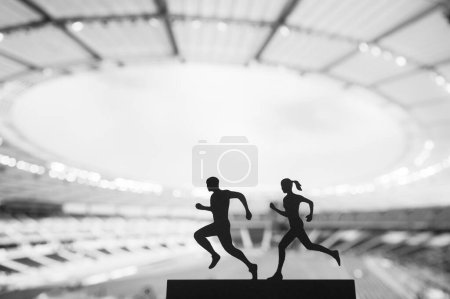 Téléchargez les photos : Des silhouettes de coureurs masculins et féminins créent un spectacle fascinant de travail d'équipe dans un stade sportif moderne. Passion partagée, photo en noir et blanc - en image libre de droit