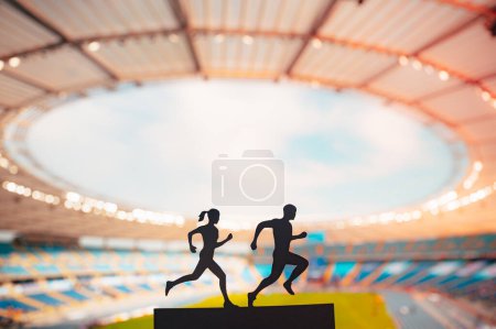 Foto de Un dúo dinámico: siluetas de un corredor masculino y femenino, mostrando excelencia atlética contra un estadio deportivo moderno - Imagen libre de derechos