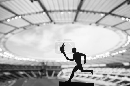 Silueta del atleta masculino que lleva el relevo de la antorcha, iluminando la pista moderna y el estadio de campo. Una cautivadora instantánea para el juego de verano 2024 en París.